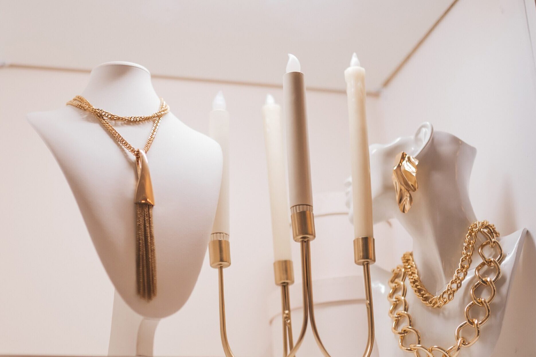 Amaranth dressing room boutique copy space boudoir table peach ecru apricot.Elegance interior with console table lavender blush modern in coral puce soft-hued neutral.Beautiful art mannequin heads on wardrobe shelves with beads from platinum silver for stylish fashion girl fashionista jewelry various set holders with gold chain jewelry.?lose-up beautiful jewelery diamonds pearl necklace earrings rings bracelets in jewelry box.Paper bag Chanel shop shopping on women table near mirror and candles